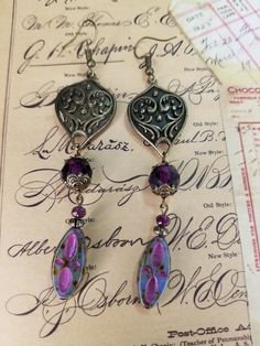 30x21mm fancy bronze shield link. 20x9mm pressed Czech glass patterned oval, blue opal picasso pink wash. 10 & 4mm faceted glass rounds plum. 4mm corrugated metal spacers. Antique bronze bead caps and fishhook ear wires. Artistic Nickel-free Purple Jewelry, Artistic Purple Nickel-free Jewelry, Artistic Jewelry With Czech Glass And Ear Wire, Silver Czech Glass Jewelry For Crafting, Artistic Czech Glass Jewelry With Ear Wire, Nickel-free Czech Glass Artisan Jewelry, Artisan Nickel-free Czech Glass Jewelry, Czech Glass Oval Beads Jewelry For Jewelry Making, Ornate Handmade Purple Jewelry