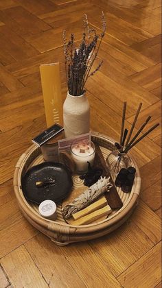 an assortment of items are arranged in a basket on the floor next to a candle