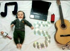 a baby laying on top of a bed next to a guitar and headphones