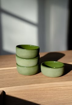 three green bowls sitting on top of a wooden table