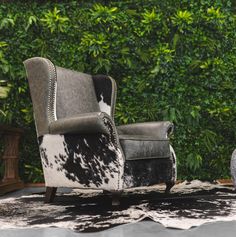 a chair and ottoman in front of a green wall with plants on it's sides