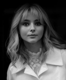 a black and white photo of a woman with long blonde hair wearing a collared shirt