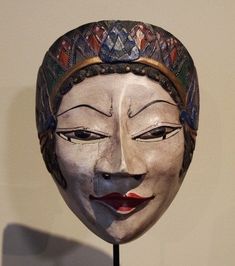 a white mask with an elaborate headdress on it's face is displayed