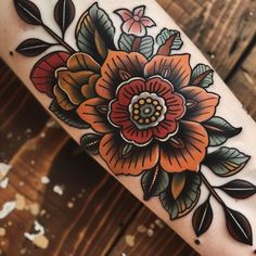 an orange flower on the arm with leaves and flowers around it's center piece