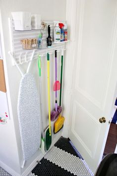 there is a rack with cleaning supplies in the corner and two brooms next to it