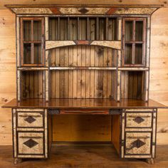 an old wooden desk with glass doors and drawers on the top, against a wood paneled wall