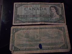 two canadian currency bills sitting next to each other on a black surface with the words canada printed on it