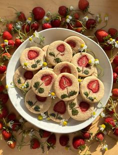 strawberry shortbreads on a plate surrounded by flowers and daisies