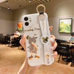 a person holding up a cell phone case with mickey mouse stickers on it