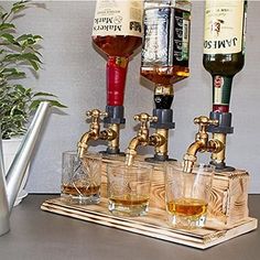 three different types of alcohol being poured into shot glasses on a wooden tray with metal faucets