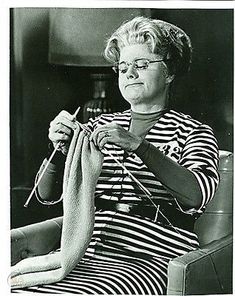 an older woman knitting while sitting in a chair