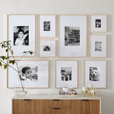 a wall with many pictures on it and a vase filled with flowers in front of it