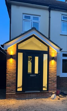 a black door is lit up in front of a house