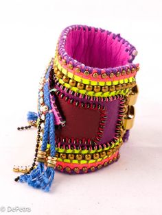 multicolored bracelets with bells and tassels on white background, close up