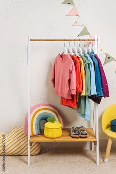 a child's clothing rack with clothes hanging on it and other items in the foreground