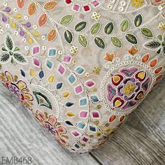 a close up of a decorative pillow on a wooden surface