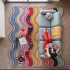 a woman laying on top of a blue couch next to a wall with multicolored stripes