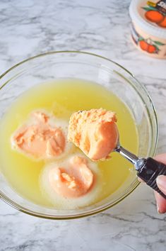 someone holding a spoon with some ice cream in it on top of a bowl filled with liquid