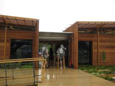 two people are standing in the doorway of a wooden building that is made out of wood planks