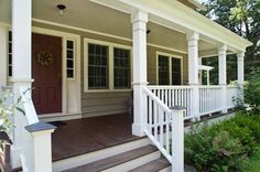 a porch with steps leading up to the front door and two doors on each side