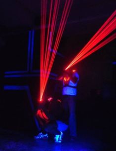 two people standing in the dark with red and blue lasers