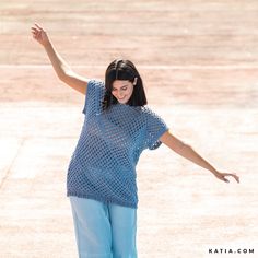 a woman riding a skateboard on top of a cement ground with her arms outstretched