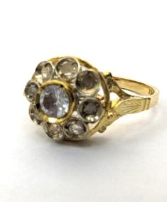 an antique ring with three stones in it on a white surface, the middle one is yellow gold