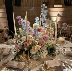 a centerpiece with candles and flowers on a table in a banquet or wedding reception