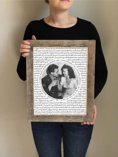 a woman holding up a framed photo in front of her face with the words on it