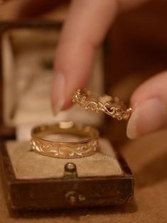 a person is holding a gold ring in their hand and it's inside an open box