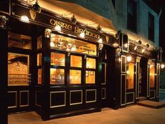 the outside of a restaurant lit up at night with lights shining on it's windows