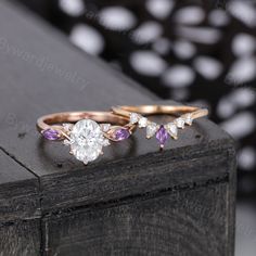 three different colored diamond rings sitting on top of a wooden table