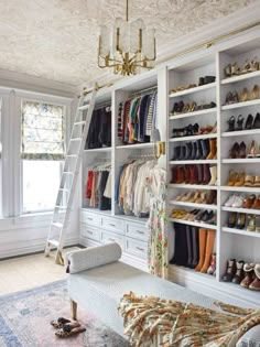 a white closet filled with lots of shoes and other items next to a ladder that is hanging from the ceiling