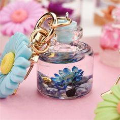 a flower keychain is sitting in a glass jar on a table with other flowers