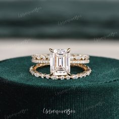 an emerald colored diamond ring sits on top of a green velvet box, with the band around it's edge