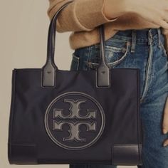 Tory Burch | Black Patent Ella Small Tote Posh Mini Tote That Boasts A High-Shine Exterior And Plenty Of Storage For Your On-The-Go Essentials. Approximate Measurements: 13.6'' W X 10.6'' H X 3.4'' D 7.4'' Handle Drop Patent Leathers Snap Closure Recycled Polyester Two Interior Compartments **In Like New Condition** Designer Tan Bags For On-the-go, Branded Hardware Tote Shoulder Bag, Coated Canvas Shoulder Bag For Errands, Medium Shoulder Bag With Dust Bag Included, Designer Satchel For Errands, Medium On-the-go Shoulder Bag, Tan Bags With Branded Hardware For Everyday Use, Tan Shoulder Bag With Removable Pouch, Medium Bags With Detachable Handle