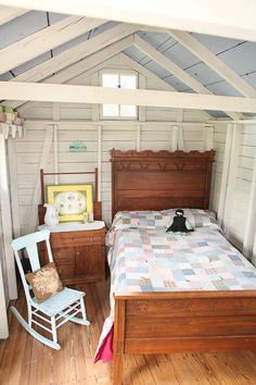 a bedroom with a bed, rocking chair and window in the corner next to it