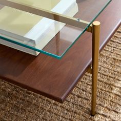 a coffee table with two books on it and a rug underneath the glass top area