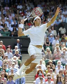 a male tennis player is jumping in the air with his racquet raised up