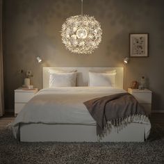 a white bed sitting under a chandelier in a bedroom