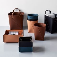 several different types of leather bags and wallets on a white surface with one bag in the middle