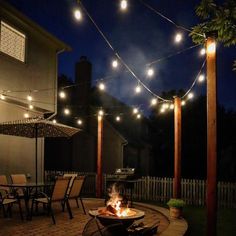 an outdoor fire pit surrounded by string lights