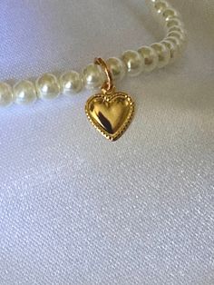 This necklace has 4mm round glass pearls. The necklace is accented with a gold heart charm. Gold Beaded Heart Necklace Gift, Gold Beaded Heart Necklace For Gift, Gold Necklaces With Heart Charm And Round Beads, Gold Heart Necklace With Pearl Charm As Gift, Gold Pearl Necklace With Heart Charm And Pendant, Gold Pearl Beaded Charm Necklaces, Gold Pearl Jewelry With Heart Charm, Gold Pearl Necklace With Heart Pendant And Beads, Gold Charm Necklace With Pearl Charm And Round Beads