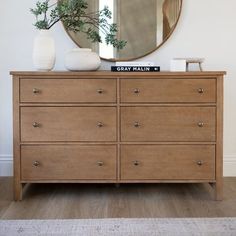 a dresser with a mirror and vase on top