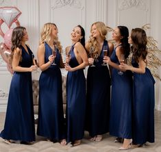 a group of women standing next to each other holding wine glasses