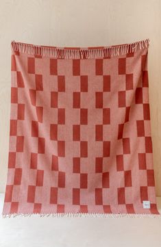 a red and white checkered blanket with fringes hanging from the side on a wall