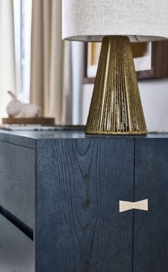 a lamp that is on top of a wooden cabinet with a bow tie on it