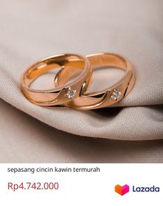 two gold wedding rings sitting on top of a white cloth with the words lazada written below it