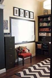 a room with a chair, bookcases and a white board on the wall