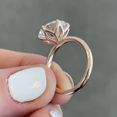 a close up of a person's hand holding a ring with a flower on it